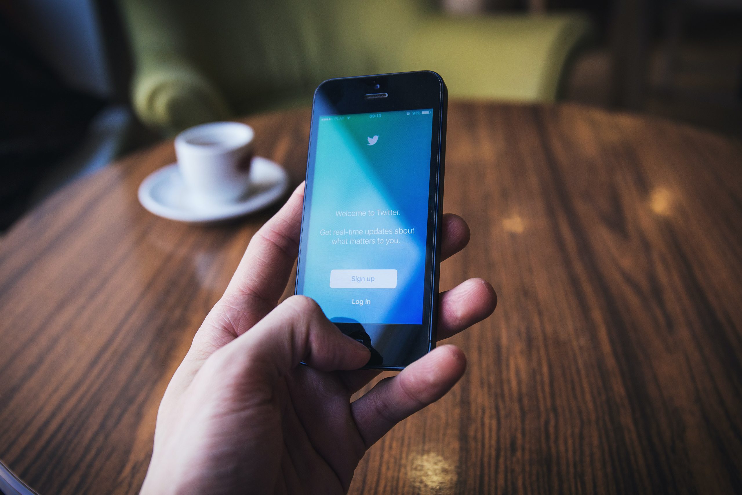 A person holding phone with the Twitter app open